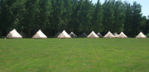 des tentes installées en campement dans un champs